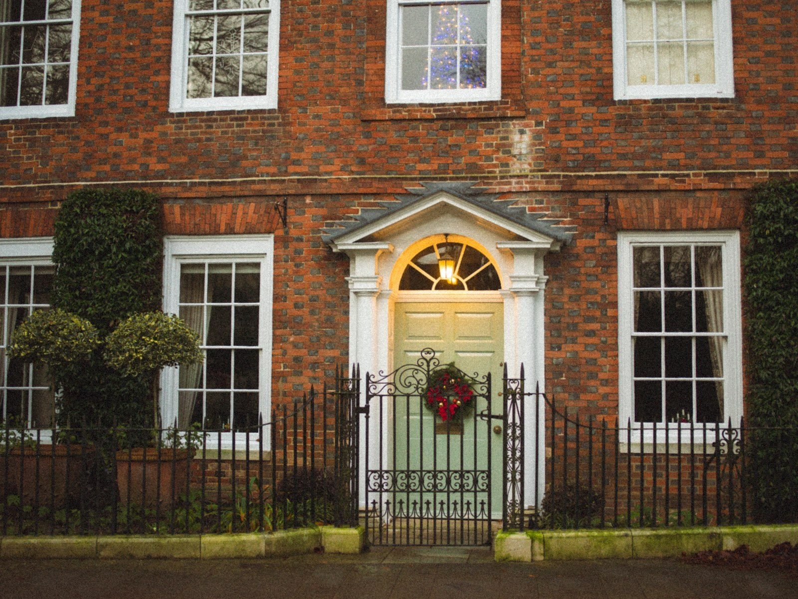 Fachada de casa de tijolos com porta verde e guirlanda de Natal