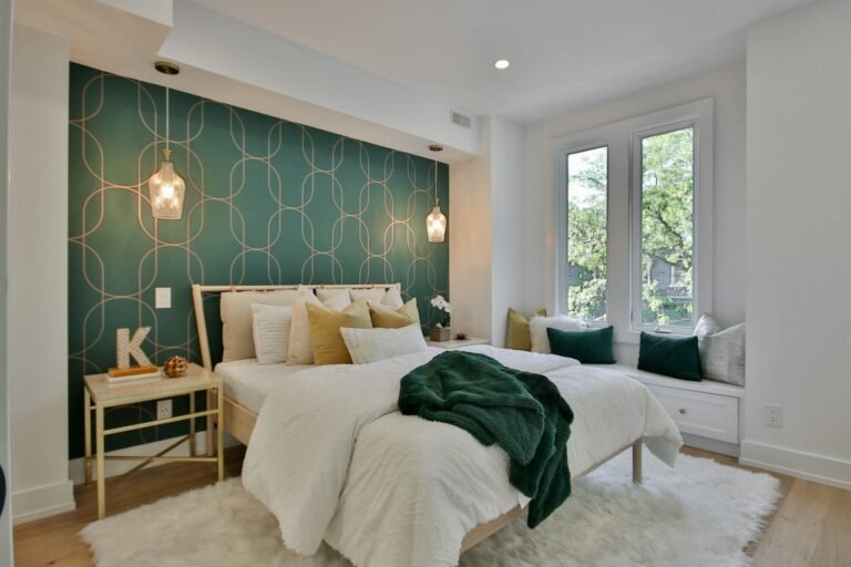 Quarto com parede de destaque em papel de parede verde com estampa geométrica dourada atrás da cama