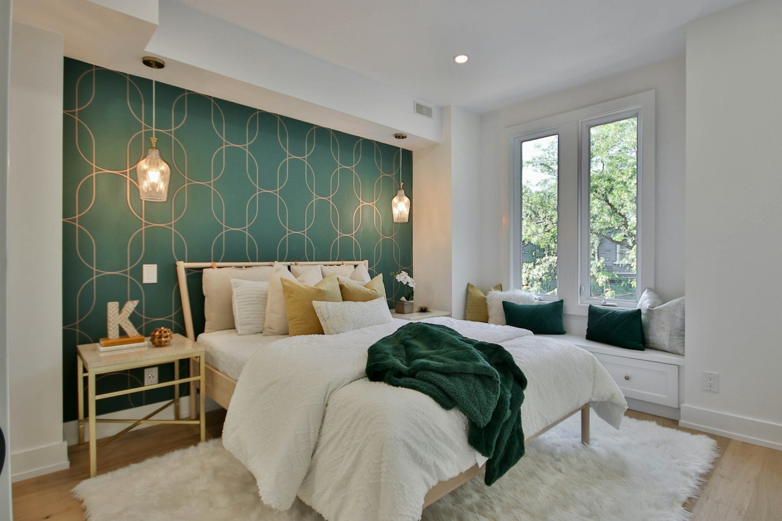 Quarto com parede de destaque em papel de parede verde com estampa geométrica dourada atrás da cama